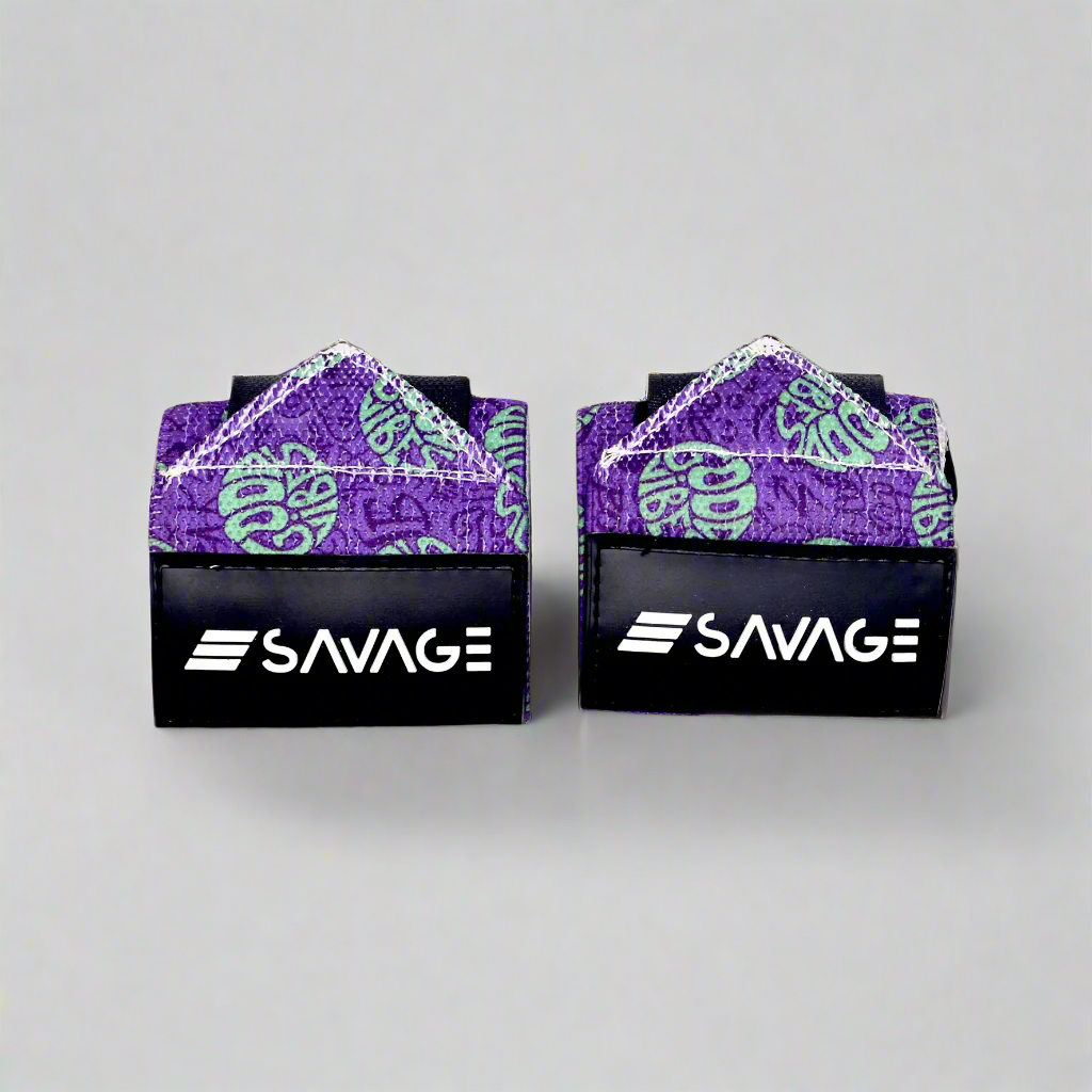 Two black and purple Savage branded boxing hand wraps on a gray background