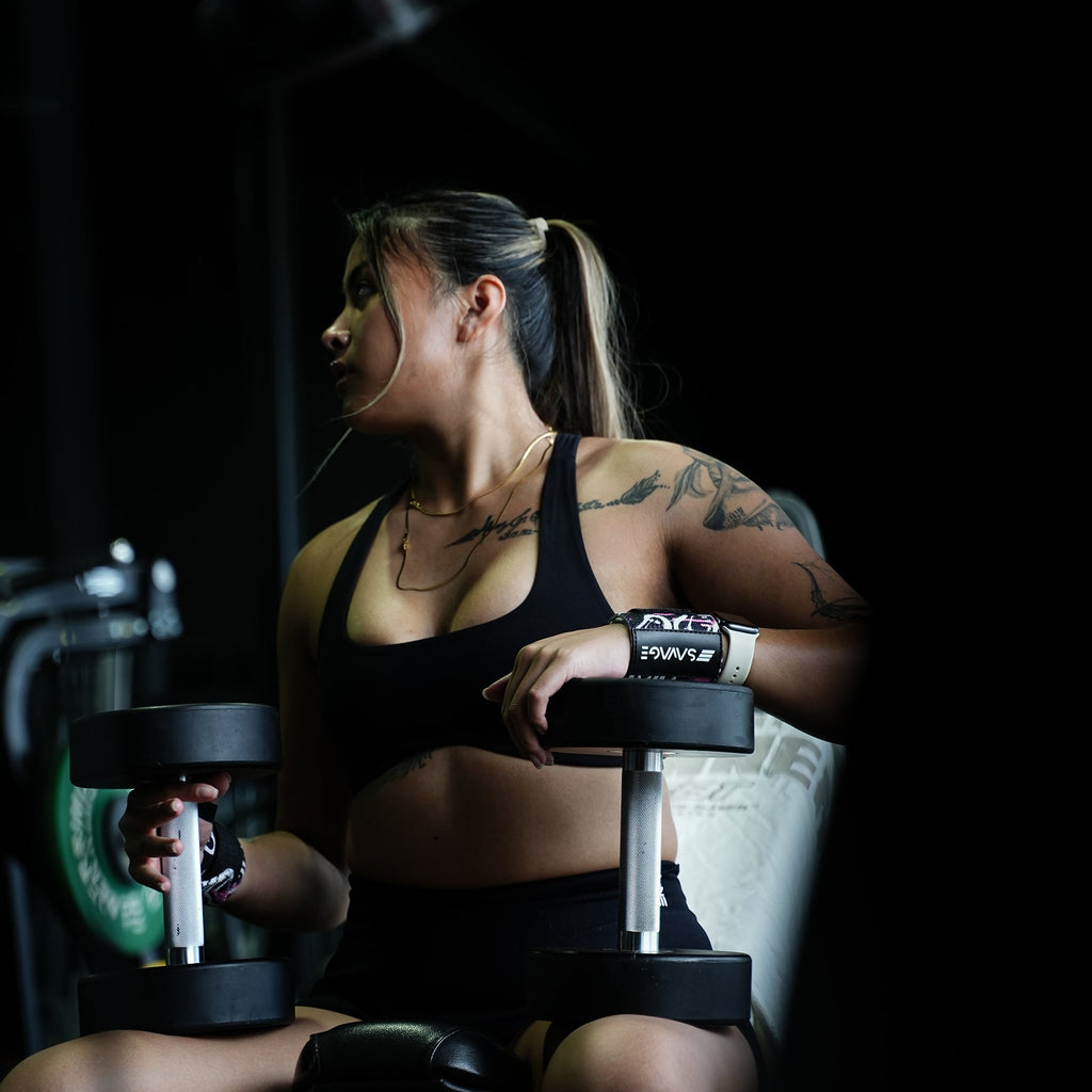 A woman lifting weights in a gym setting. Using Savage Fitness wrist wraps