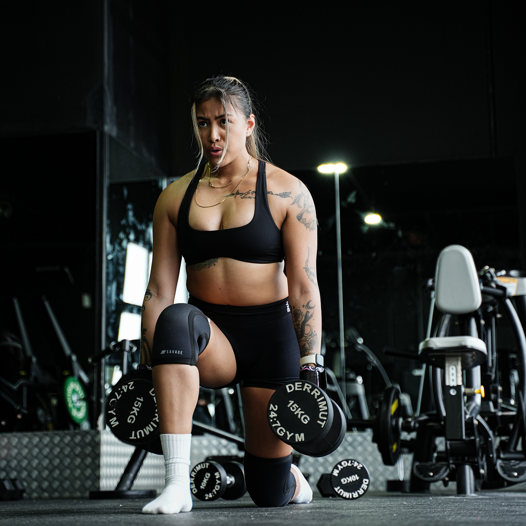 Woman doing in a gym setting putting on Savage Fitness Knee Sleeves