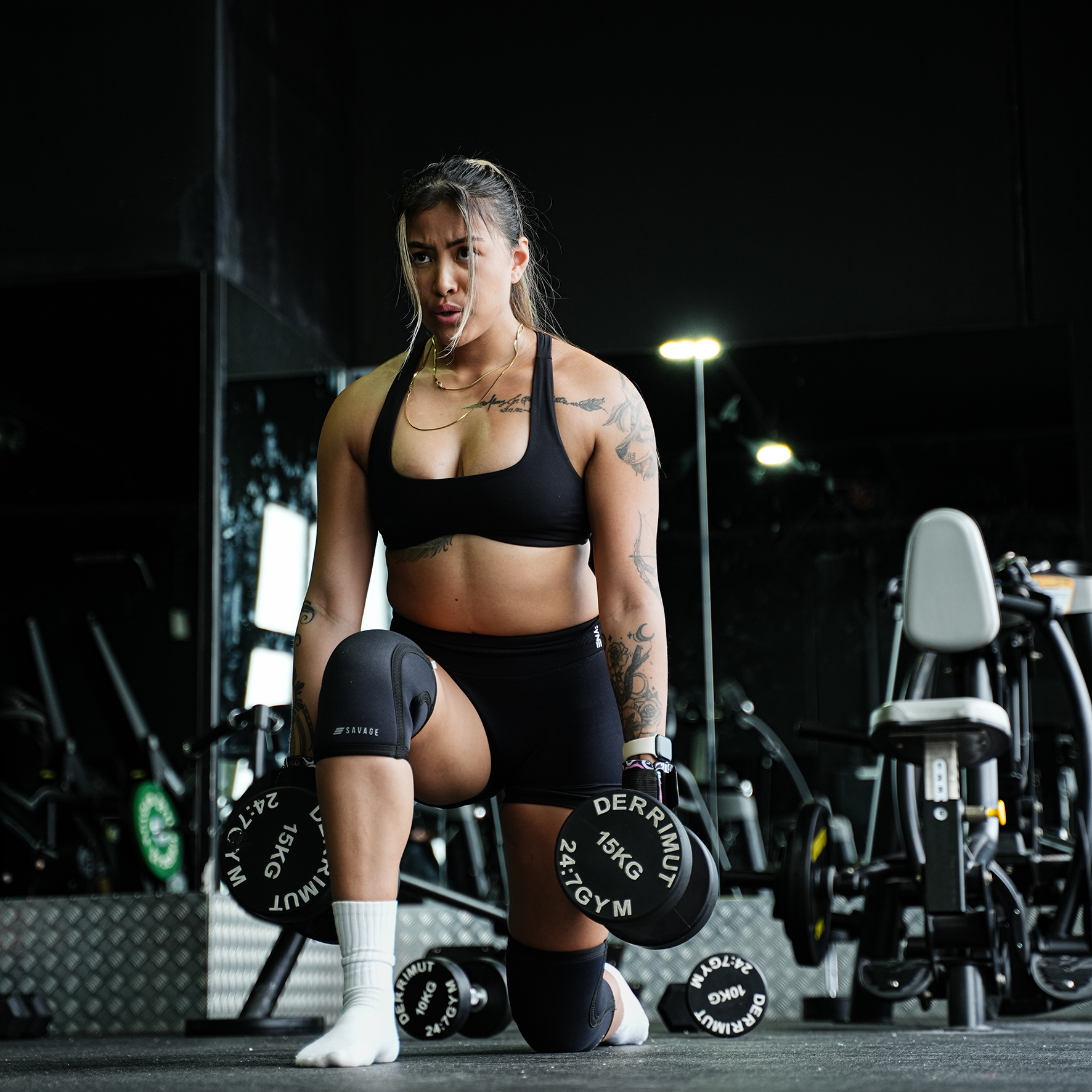 Woman doing in a gym setting putting on Savage Fitness Knee Sleeves