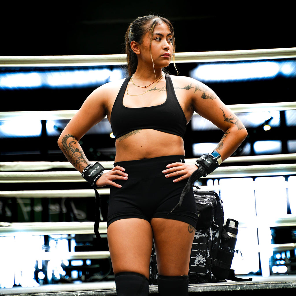 Woman in athletic wear standing in a boxing ring with gloves on