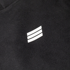 Close-up of a black textured fabric with a small white three-stripe logo centered on the chest.