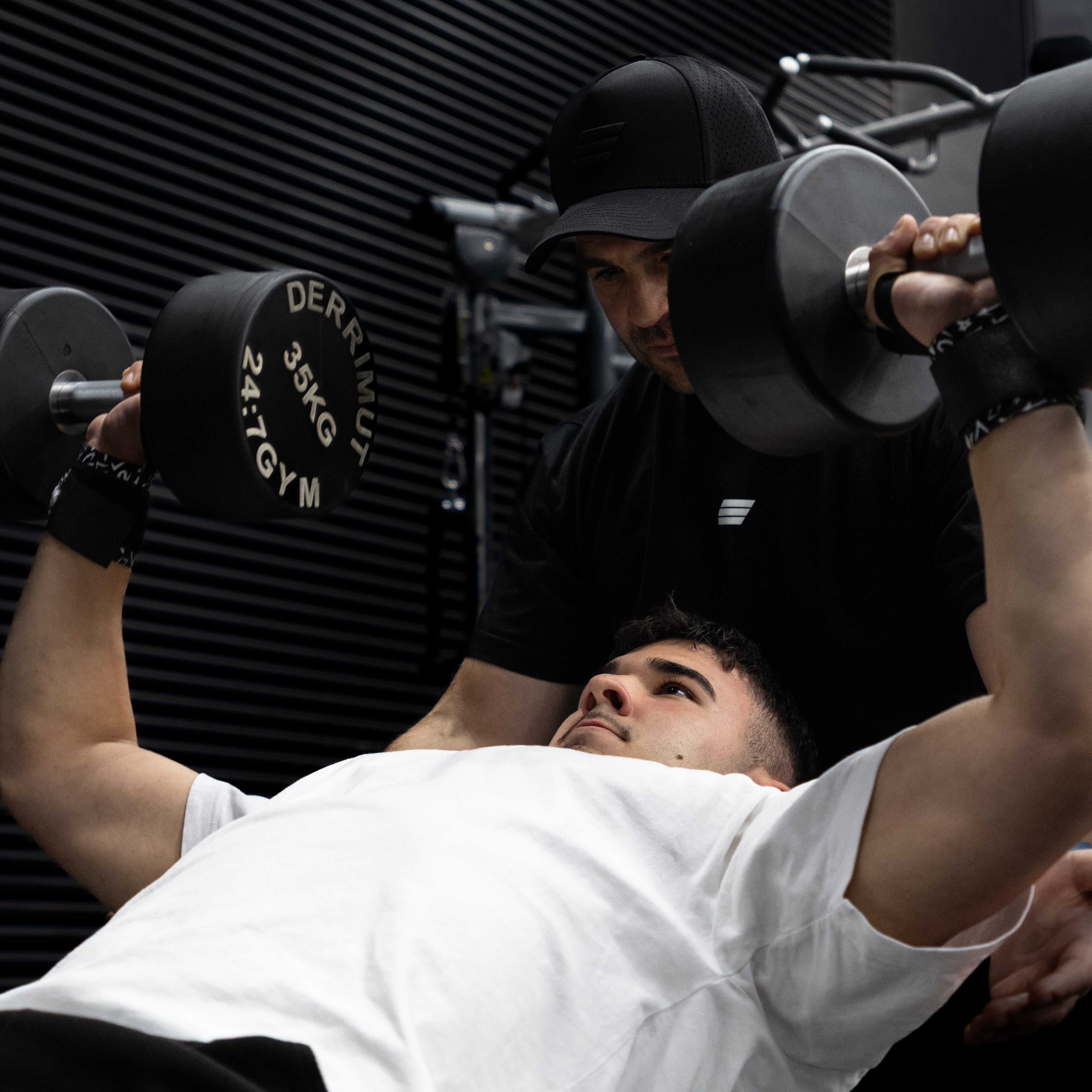 Person lifting weights with a personal trainer in a gym setting
