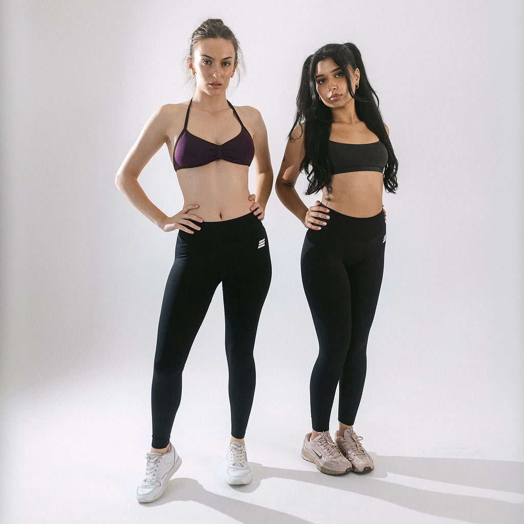 Two women wearing black seamless Savage Fitness Leggings standing against a white background